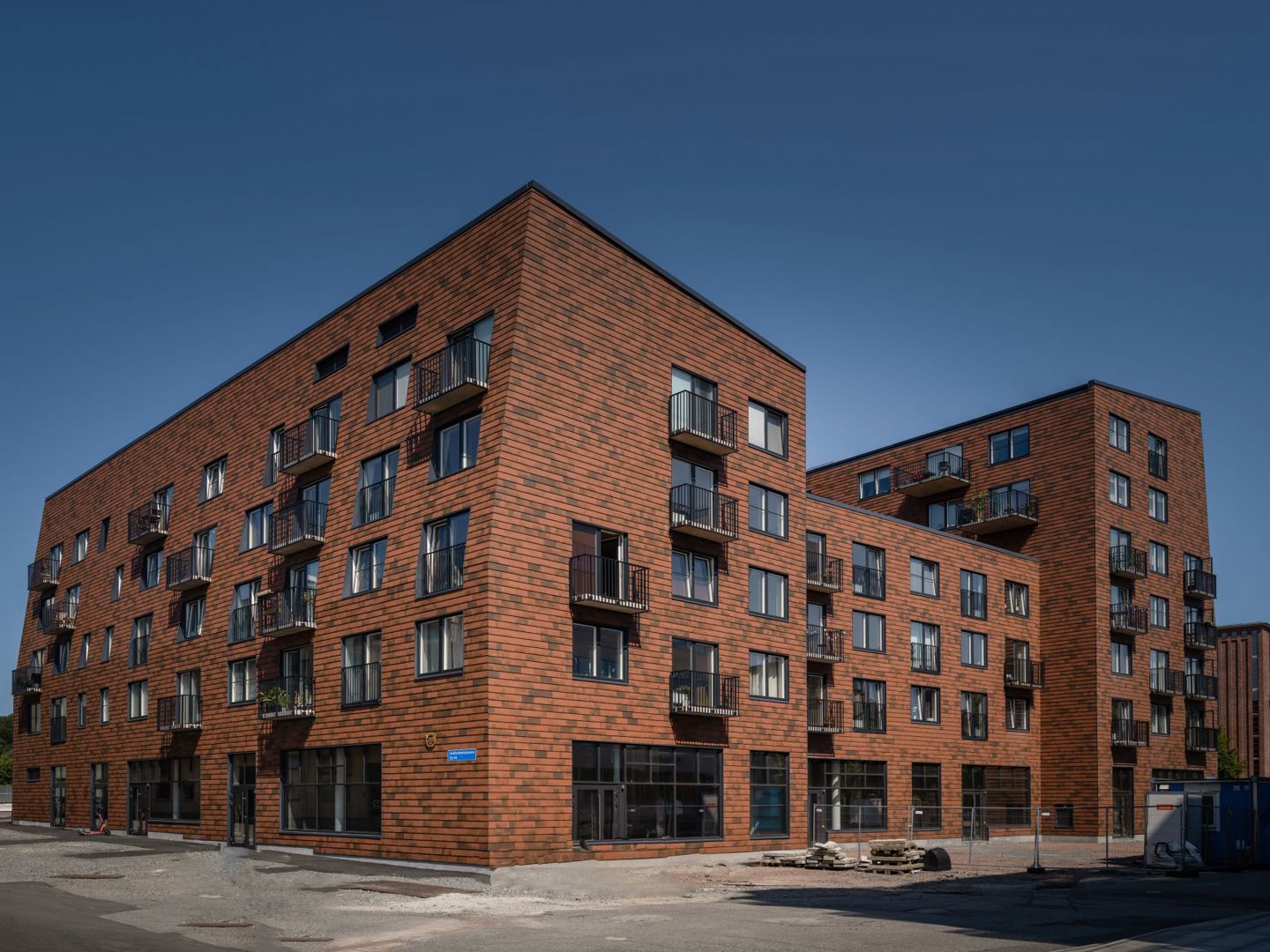 Bruna huskroppar flera våningar i Brf Blanka, fasaden i blankt skärmtegel som är lagt med shingelteknik.