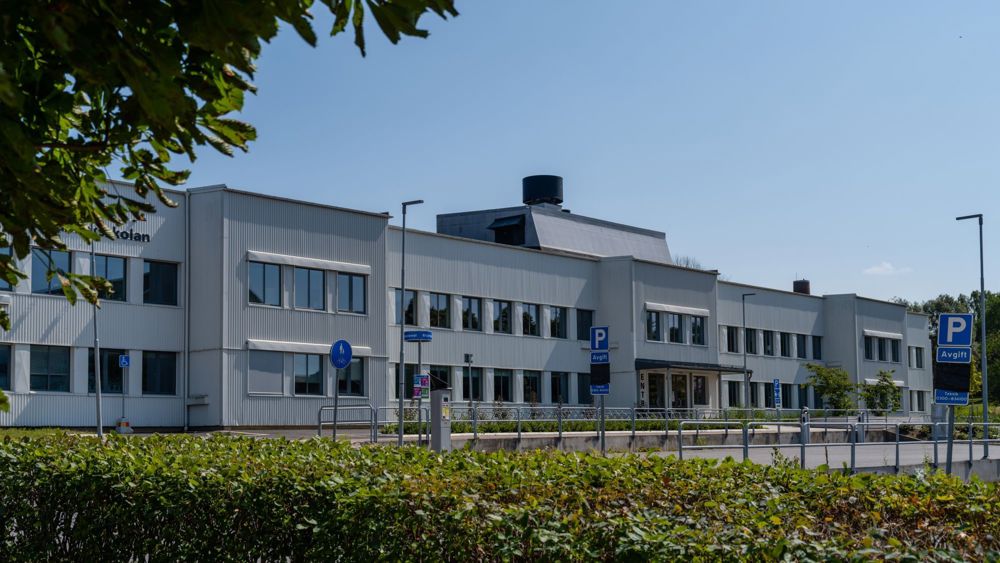 Hålabäcksskolan i Kungälv är en lång och låg ljus byggnad med gröna buskar och parkeringsskyltar omkring