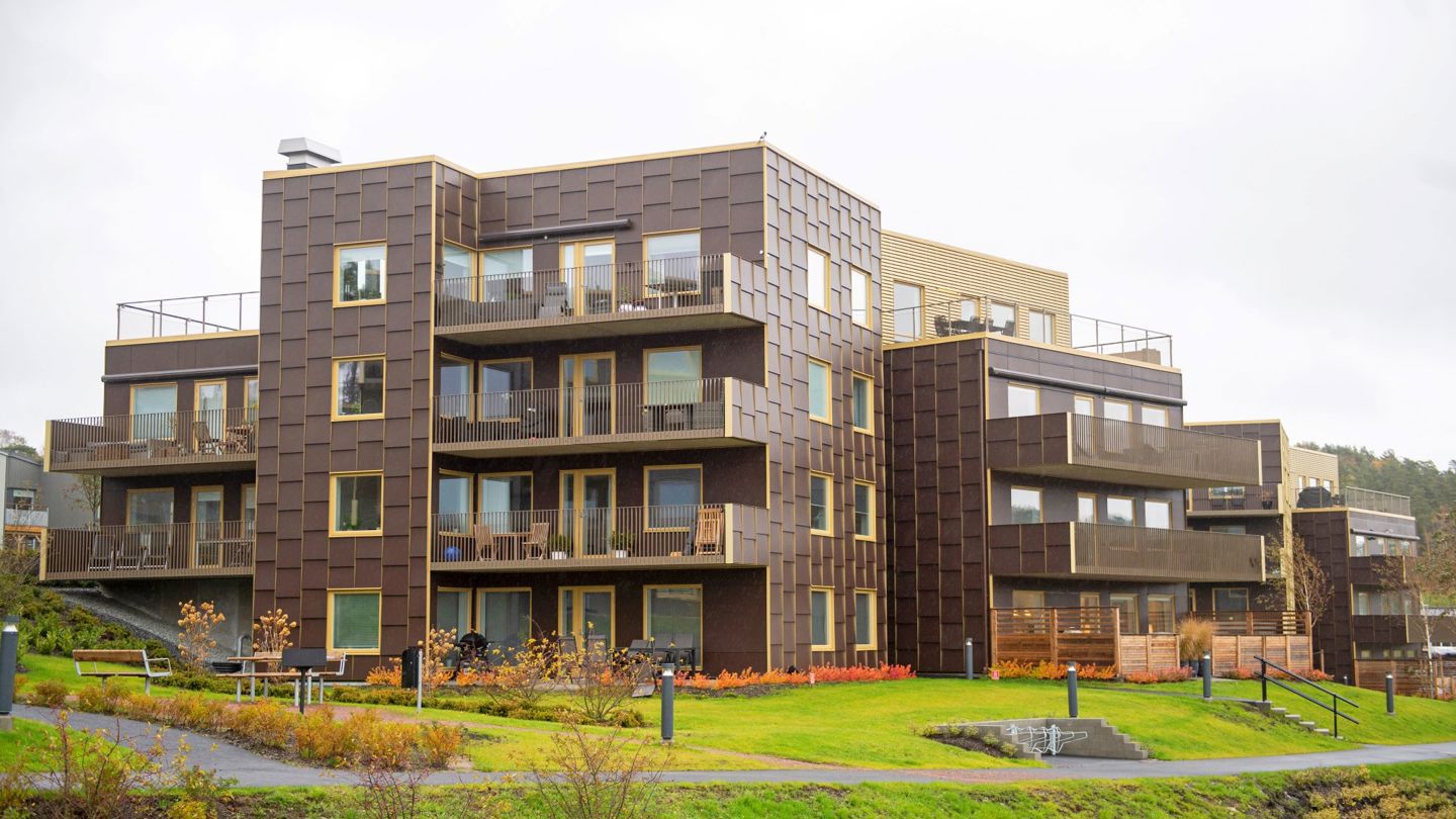 Flerbostadshus i Hills Villastad med brun fasad i tre våningar i gröna omgivningar