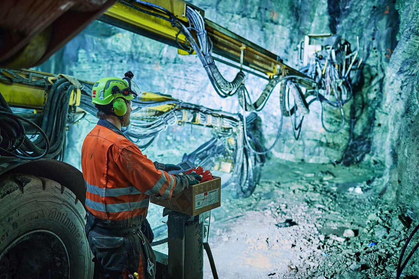 Tunneldrivning. Man i varselkläder och tunnelborr vid bergvägg.