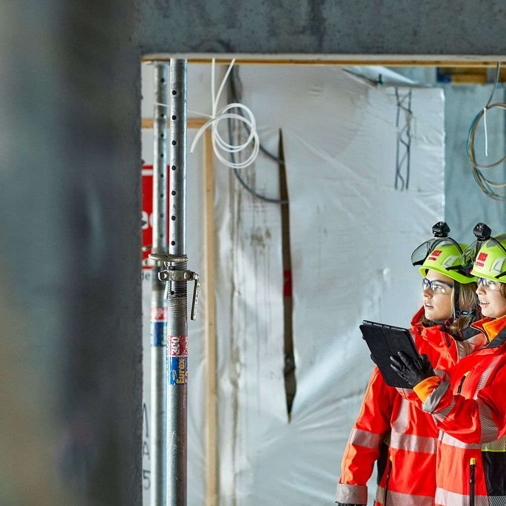 Två kvinnor i skyddskläder inspekterar ett bostadsprojekt