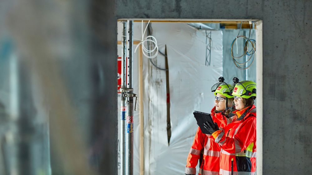 Två kvinnor i skyddskläder inspekterar ett bostadsprojekt