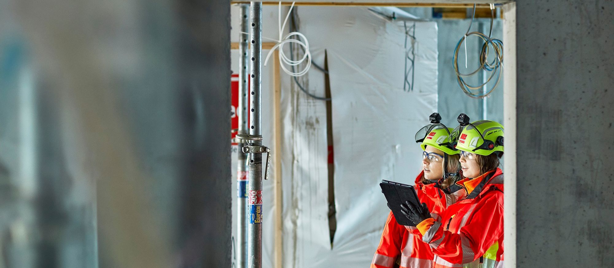 Två kvinnor i skyddskläder inspekterar ett bostadsprojekt
