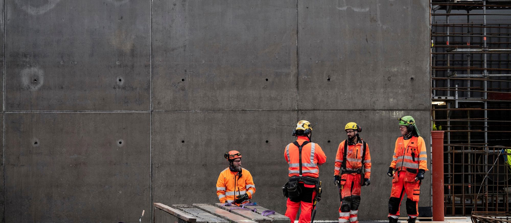 En grupp yrkesarbetare står framför en betongvägg