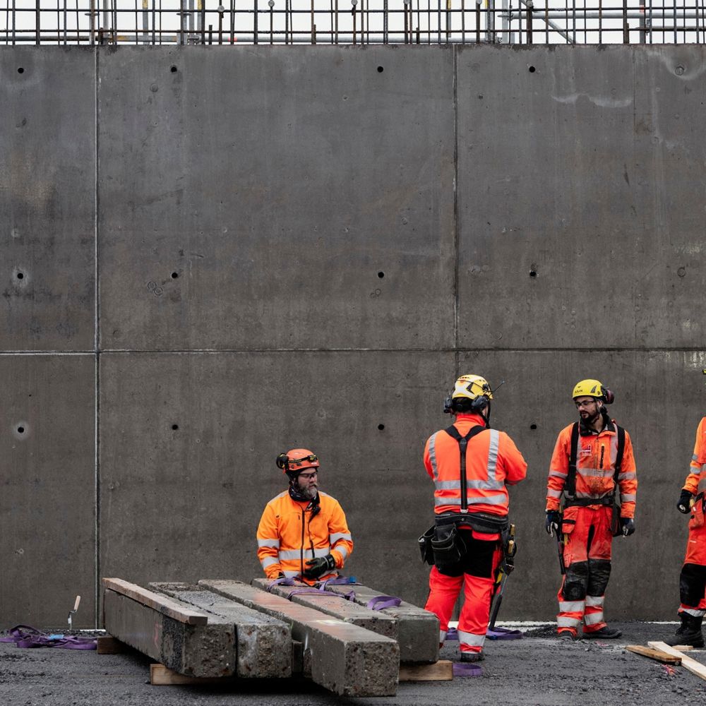 En grupp yrkesarbetare står framför en betongvägg