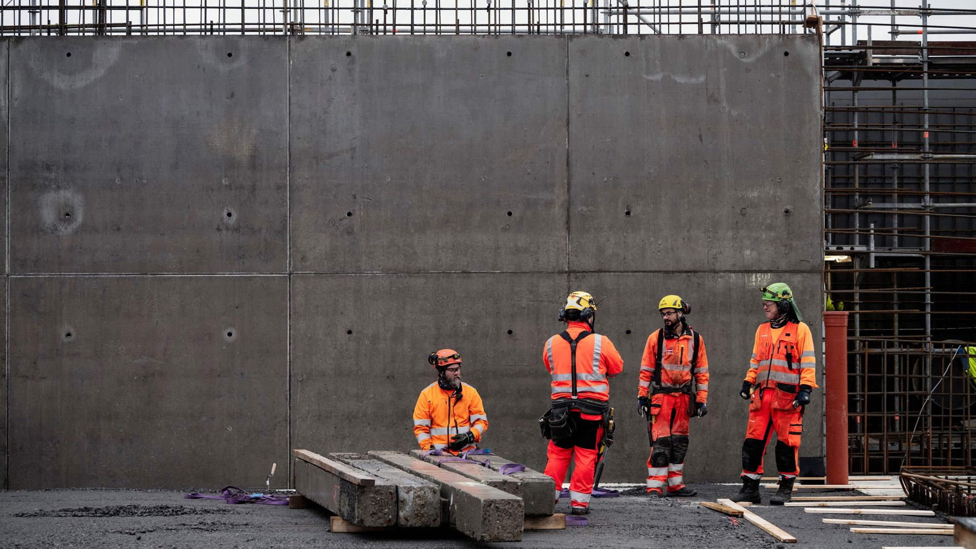 En grupp yrkesarbetare står framför en betongvägg